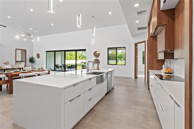 kitchen with decorative light fixtures, sink, white cabinets, black electric cooktop, and a kitchen island with sink