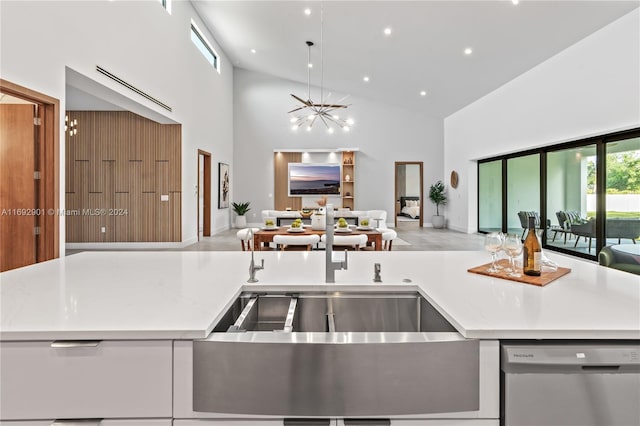 kitchen with light stone countertops, high vaulted ceiling, stainless steel dishwasher, a notable chandelier, and white cabinets