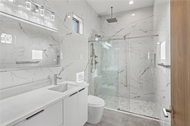 bathroom featuring a shower with door, vanity, toilet, and tile walls