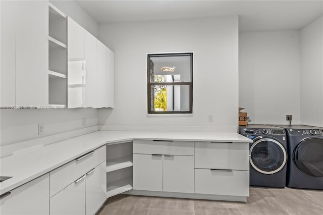 clothes washing area with washer and clothes dryer and cabinets