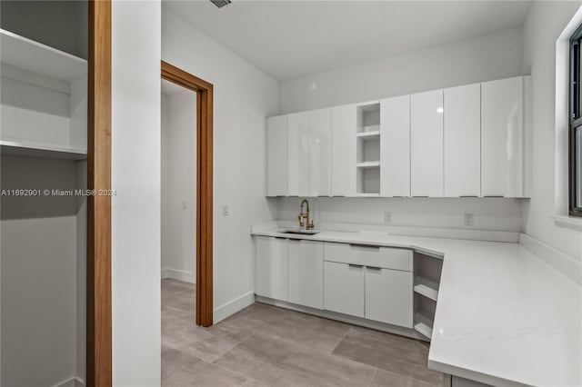 kitchen featuring white cabinets, sink, and light stone counters