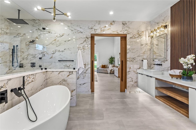 bathroom featuring a chandelier, vanity, independent shower and bath, and tile walls