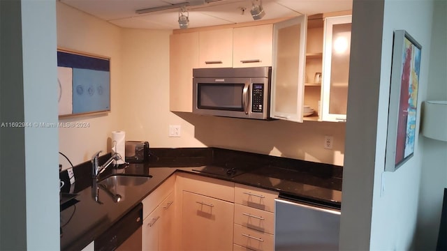 kitchen with white cabinetry, stainless steel appliances, sink, and dark stone countertops