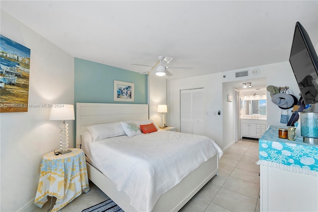 tiled bedroom featuring ceiling fan, ensuite bath, and a closet