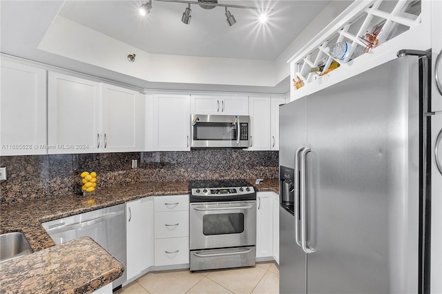 kitchen with white cabinets, dark stone countertops, appliances with stainless steel finishes, and tasteful backsplash