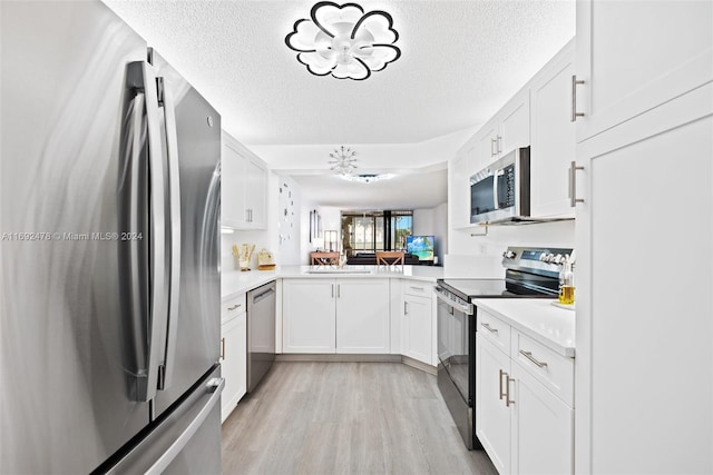 kitchen with white cabinets, light hardwood / wood-style floors, stainless steel appliances, and a textured ceiling