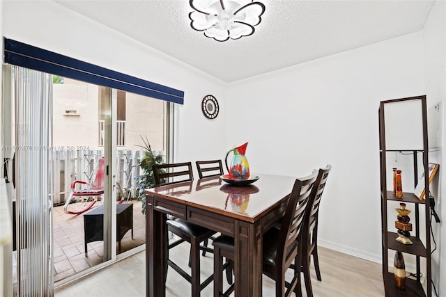 dining space with a textured ceiling and light hardwood / wood-style flooring