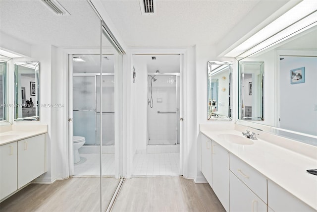 bathroom with a shower with shower door, wood-type flooring, and a textured ceiling