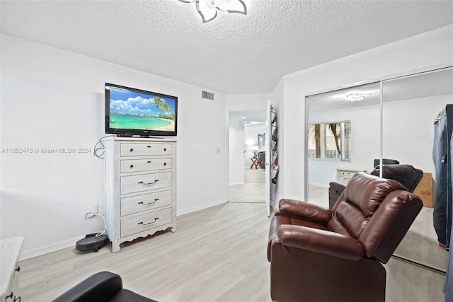 living room with a textured ceiling and light hardwood / wood-style flooring