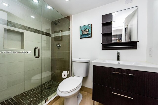 bathroom featuring toilet, vanity, tile patterned flooring, and walk in shower