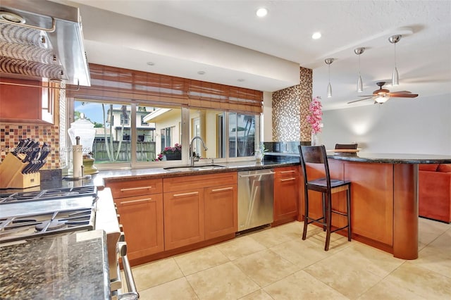 kitchen with sink, pendant lighting, dishwasher, dark stone counters, and kitchen peninsula