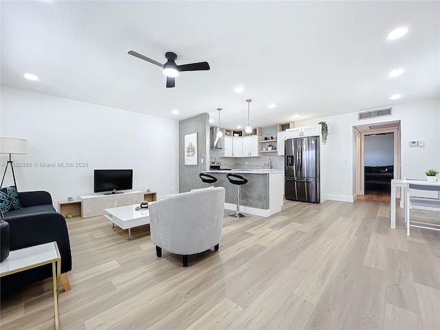 living room featuring ceiling fan, light hardwood / wood-style floors, and sink