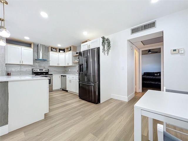 kitchen with white cabinetry, wall chimney range hood, hanging light fixtures, and appliances with stainless steel finishes