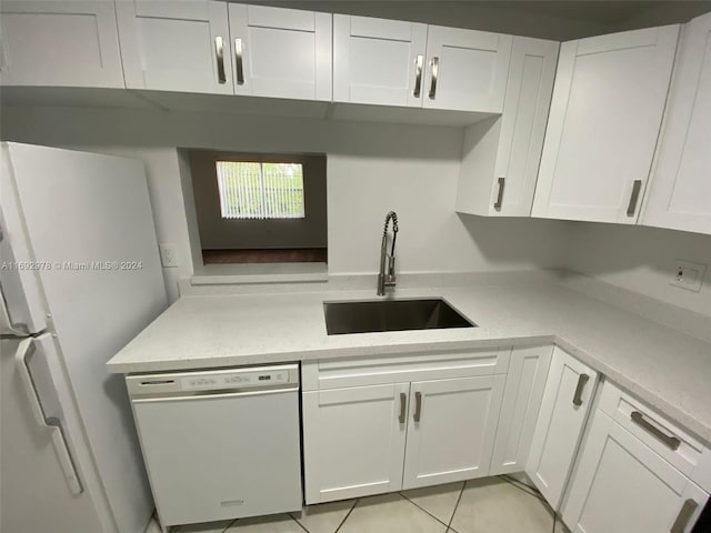 kitchen featuring light stone countertops, white appliances, sink, light tile patterned floors, and white cabinets