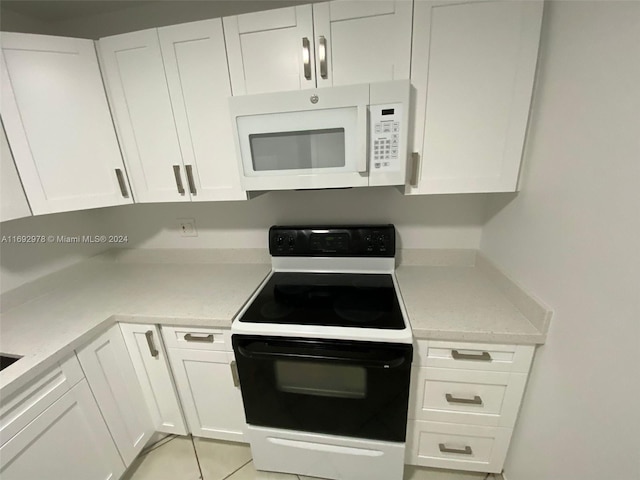 kitchen with light tile patterned floors, white cabinets, and white appliances