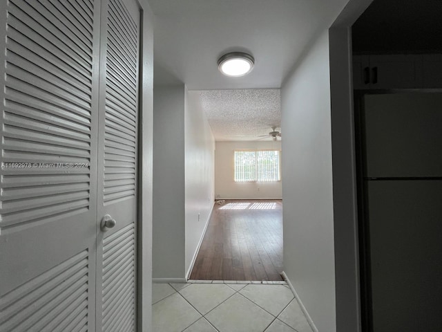 hall with a textured ceiling and light wood-type flooring