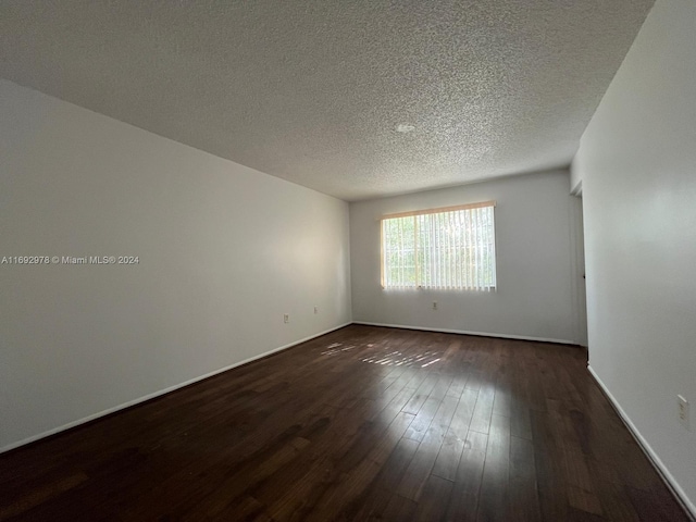 spare room featuring a textured ceiling and dark hardwood / wood-style floors