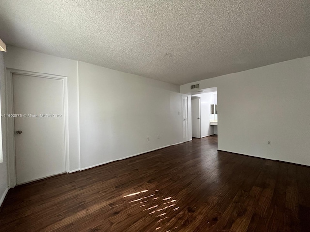 empty room with dark hardwood / wood-style flooring and a textured ceiling