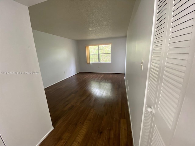 empty room with a textured ceiling and dark wood-type flooring