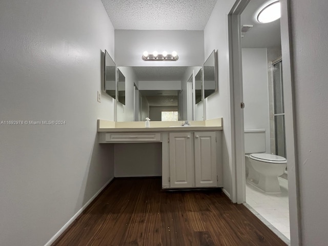 bathroom with walk in shower, hardwood / wood-style floors, a textured ceiling, toilet, and vanity