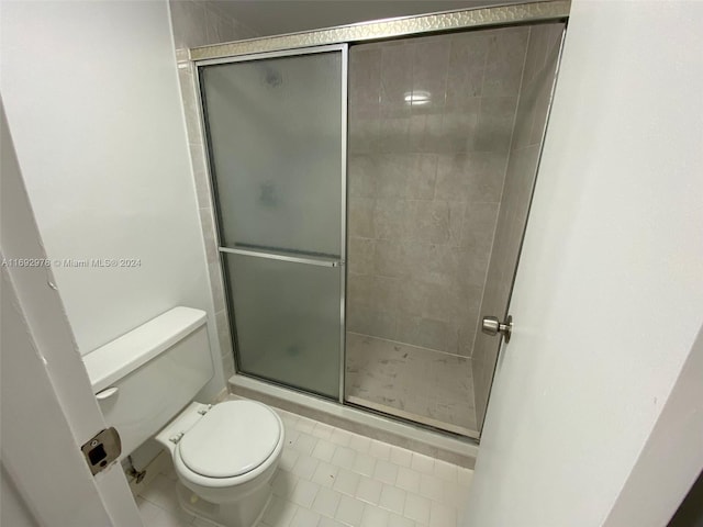 bathroom with tile patterned flooring, toilet, and an enclosed shower