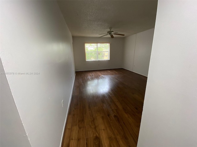 unfurnished room featuring dark hardwood / wood-style floors, ceiling fan, and a textured ceiling