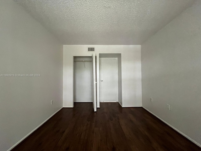 unfurnished bedroom with dark hardwood / wood-style flooring and a textured ceiling