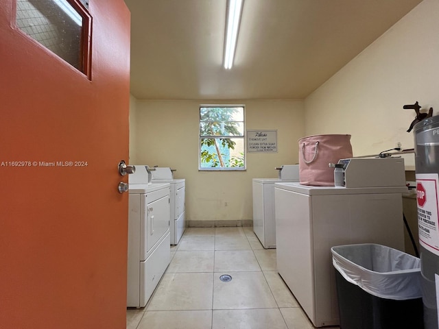 laundry room with independent washer and dryer, light tile patterned floors, and water heater