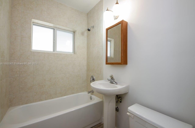 bathroom with toilet and tiled shower / bath