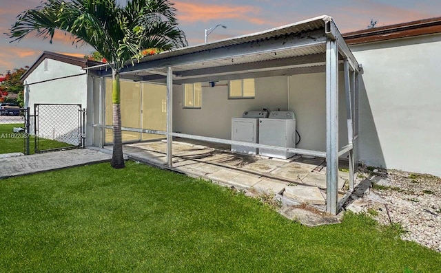 property exterior at dusk with washing machine and dryer and a yard