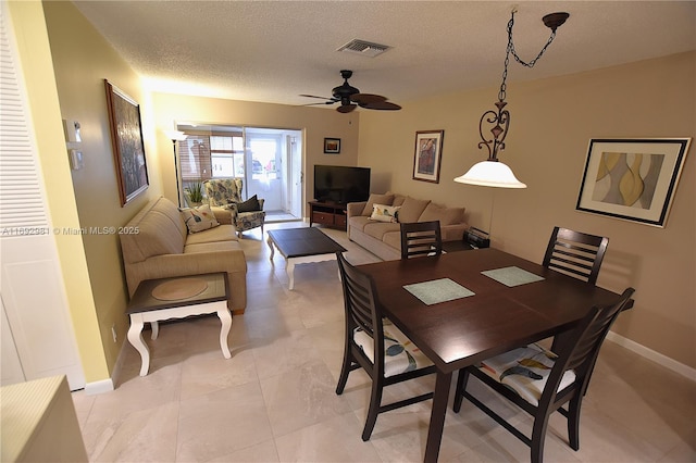 tiled dining area with a textured ceiling and ceiling fan