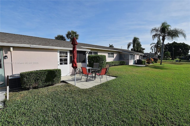 rear view of house with a lawn, central AC unit, and a patio area