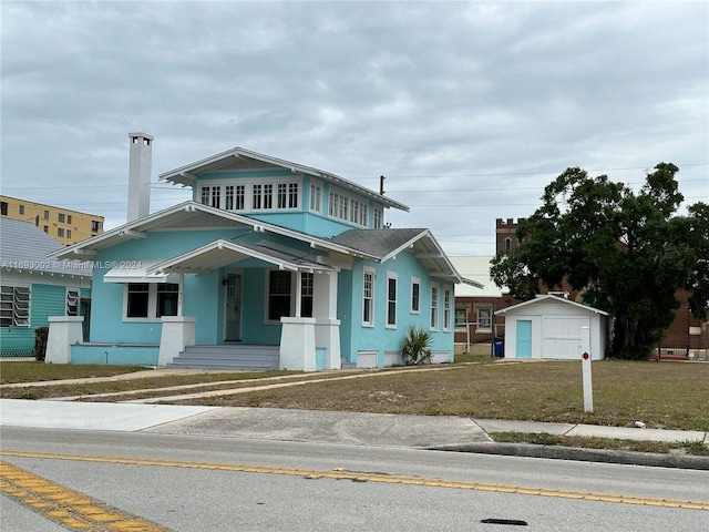 view of front facade with covered porch, a front yard, and a shed