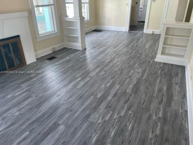 unfurnished living room featuring dark hardwood / wood-style floors and decorative columns