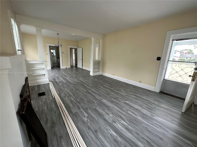 unfurnished living room with a chandelier, ornate columns, and dark hardwood / wood-style flooring