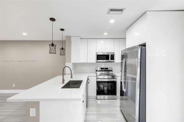 kitchen with stainless steel appliances, sink, decorative light fixtures, light hardwood / wood-style flooring, and white cabinets