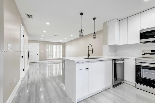 kitchen featuring white cabinetry, appliances with stainless steel finishes, decorative light fixtures, sink, and kitchen peninsula