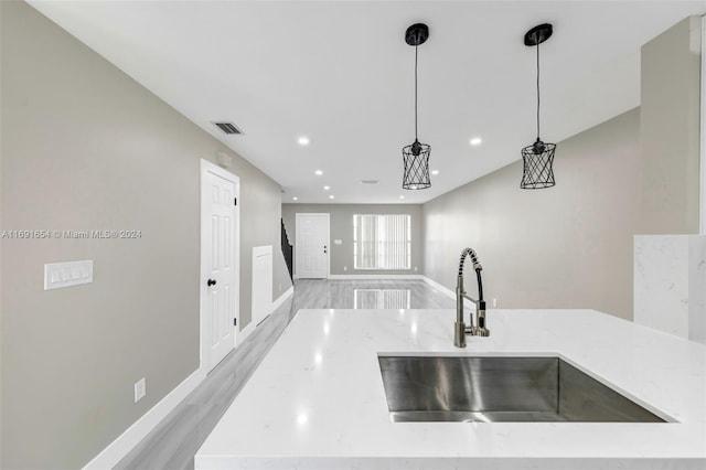 kitchen featuring hanging light fixtures, sink, and light wood-type flooring