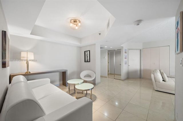 living room featuring light tile patterned flooring and a tray ceiling