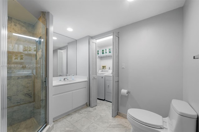 bathroom with toilet, vanity, washing machine and clothes dryer, and a shower with shower door