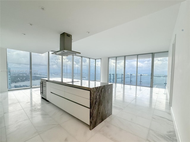 hall with expansive windows, a wealth of natural light, a beach view, and a water view