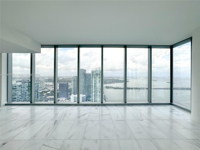 unfurnished room with expansive windows and a water view