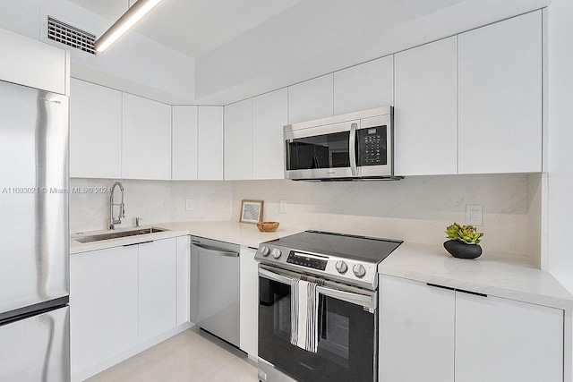 6301 Collins Ave Unit 1508, Miami Beach, FL 33141 - kitchen featuring stainless steel appliances, a sink, backsplash, light countertops, and white cabinetry