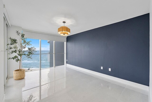 tiled empty room featuring a beach view and a water view