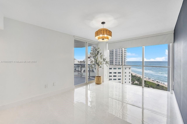 spare room with a wall of windows, a beach view, and a water view