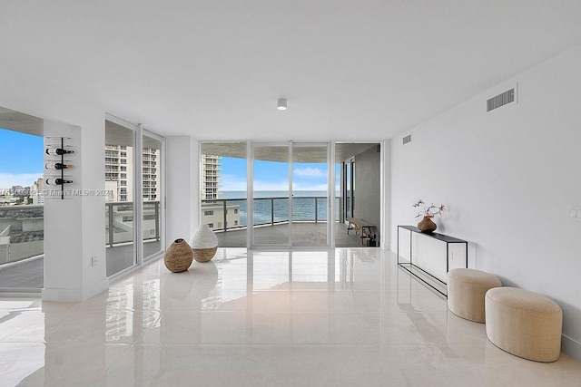 spare room featuring a wall of windows, plenty of natural light, and a water view