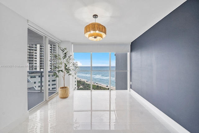 6301 Collins Ave Unit 1508, Miami Beach, FL 33141 - tiled empty room featuring a wall of windows, a water view, and baseboards