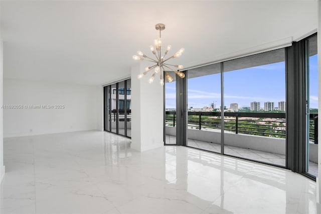 empty room featuring a chandelier, a view of city, marble finish floor, and expansive windows