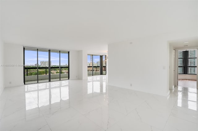 spare room featuring marble finish floor and expansive windows