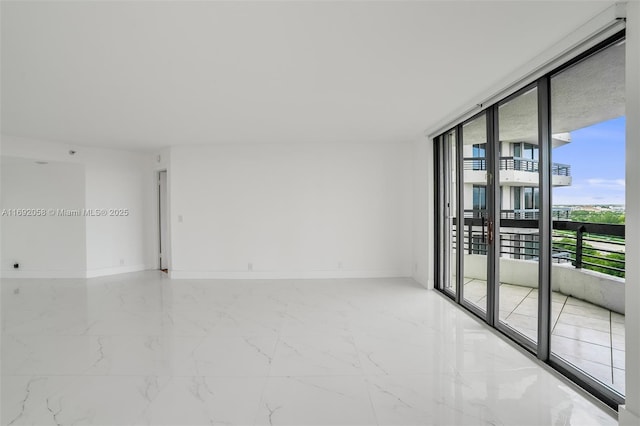 unfurnished room featuring marble finish floor, floor to ceiling windows, and baseboards